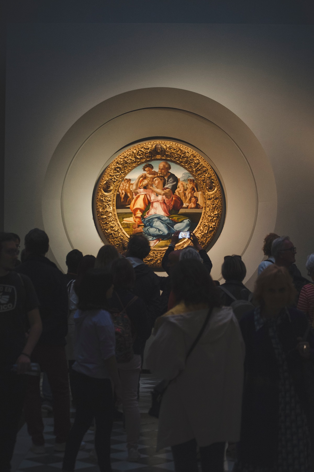 Los visitantes se reúnen en un museo de arte oscuro alrededor de una pintura iluminada por luces