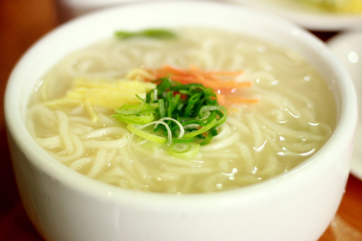 Sopa de fideos coreana con guarnición de cebollino y zanahorias en rodajas