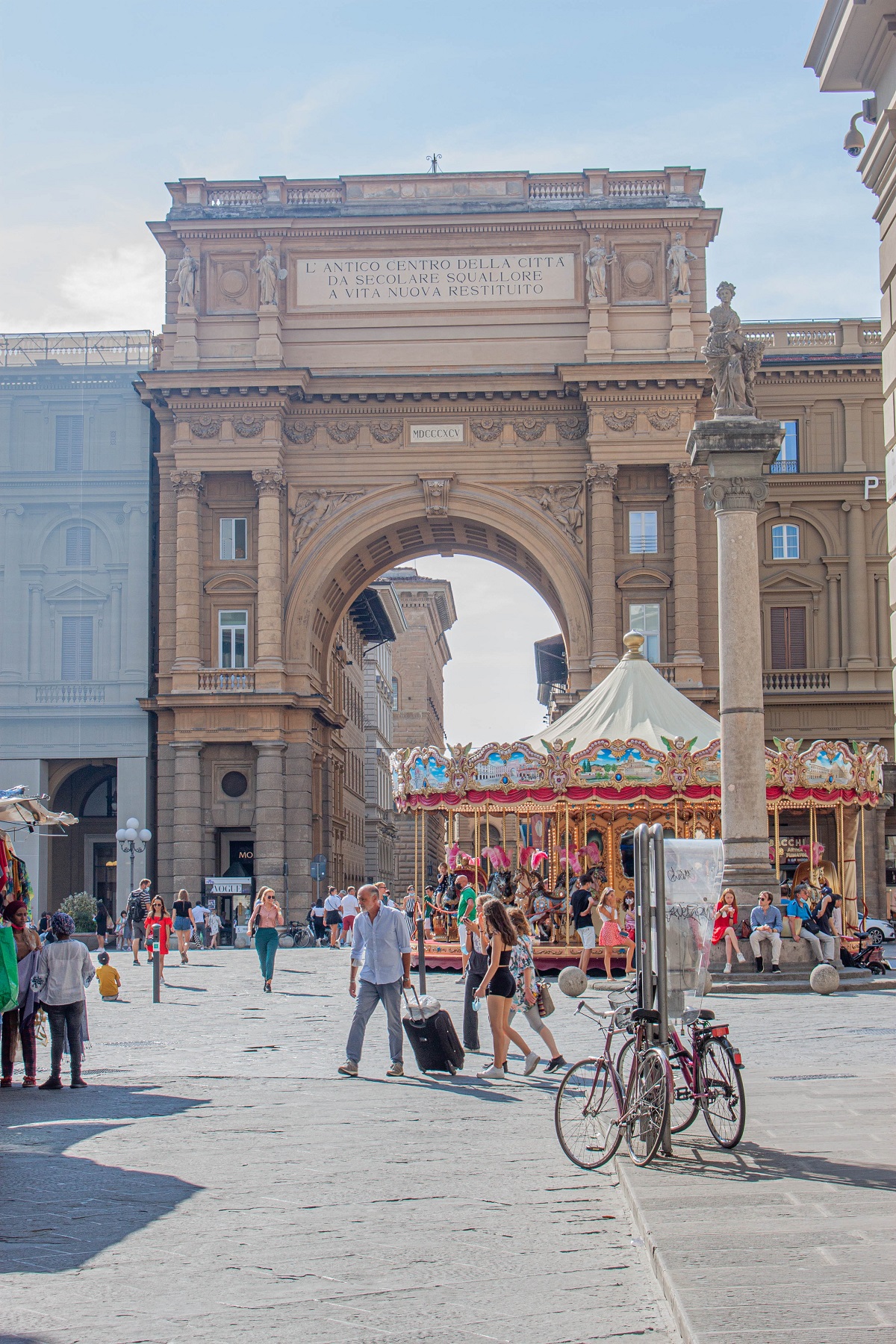 Turistas en Florencia arrastran sus maletas por una famosa plaza en Italia con bicicletas a su lado