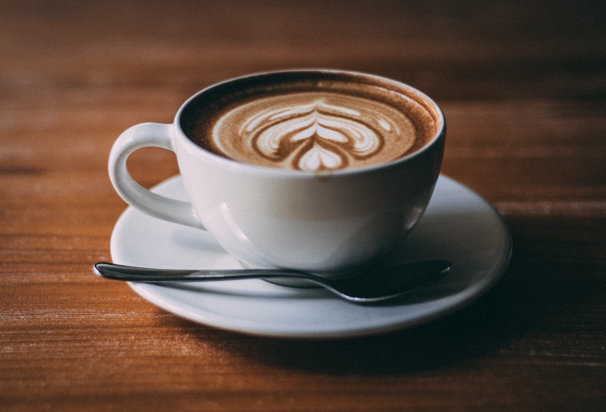 Latte en una pequeña taza blanca encima de una mesa de madera