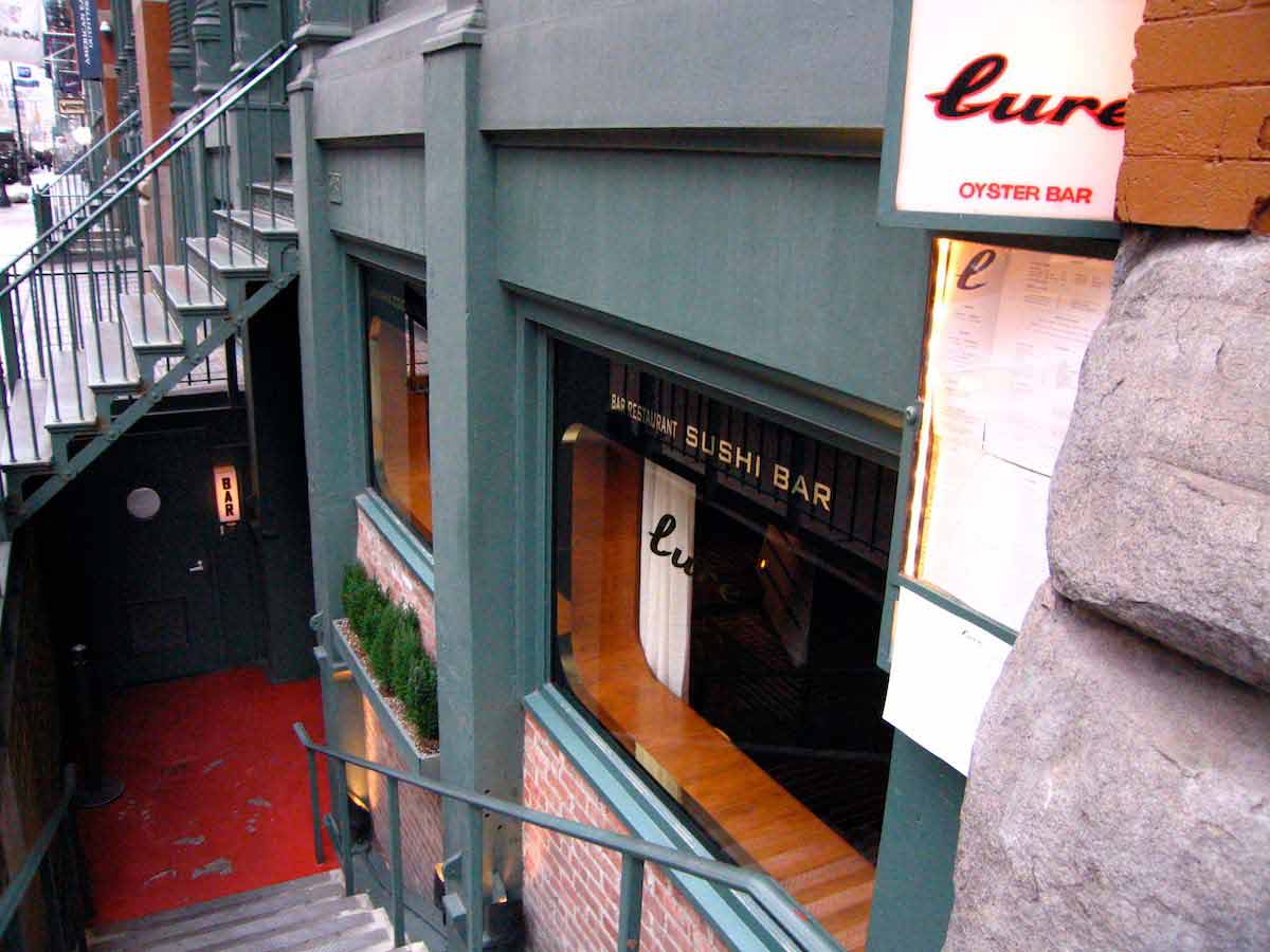 Escaleras que conducen a un restaurante de mariscos con ladrillo rojo y paneles exteriores de color verde oscuro.