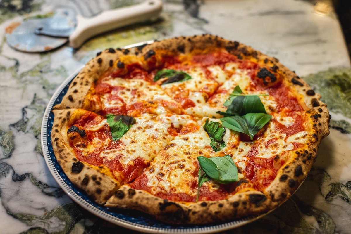 Pizza entera adornada con albahaca fresca
