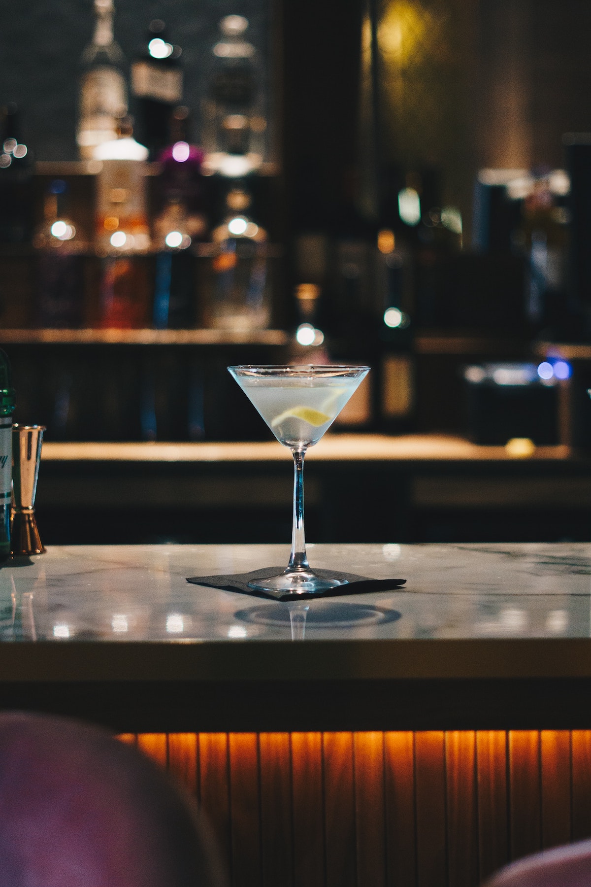 Martini adornado con cáscara de limón encima de una barra
