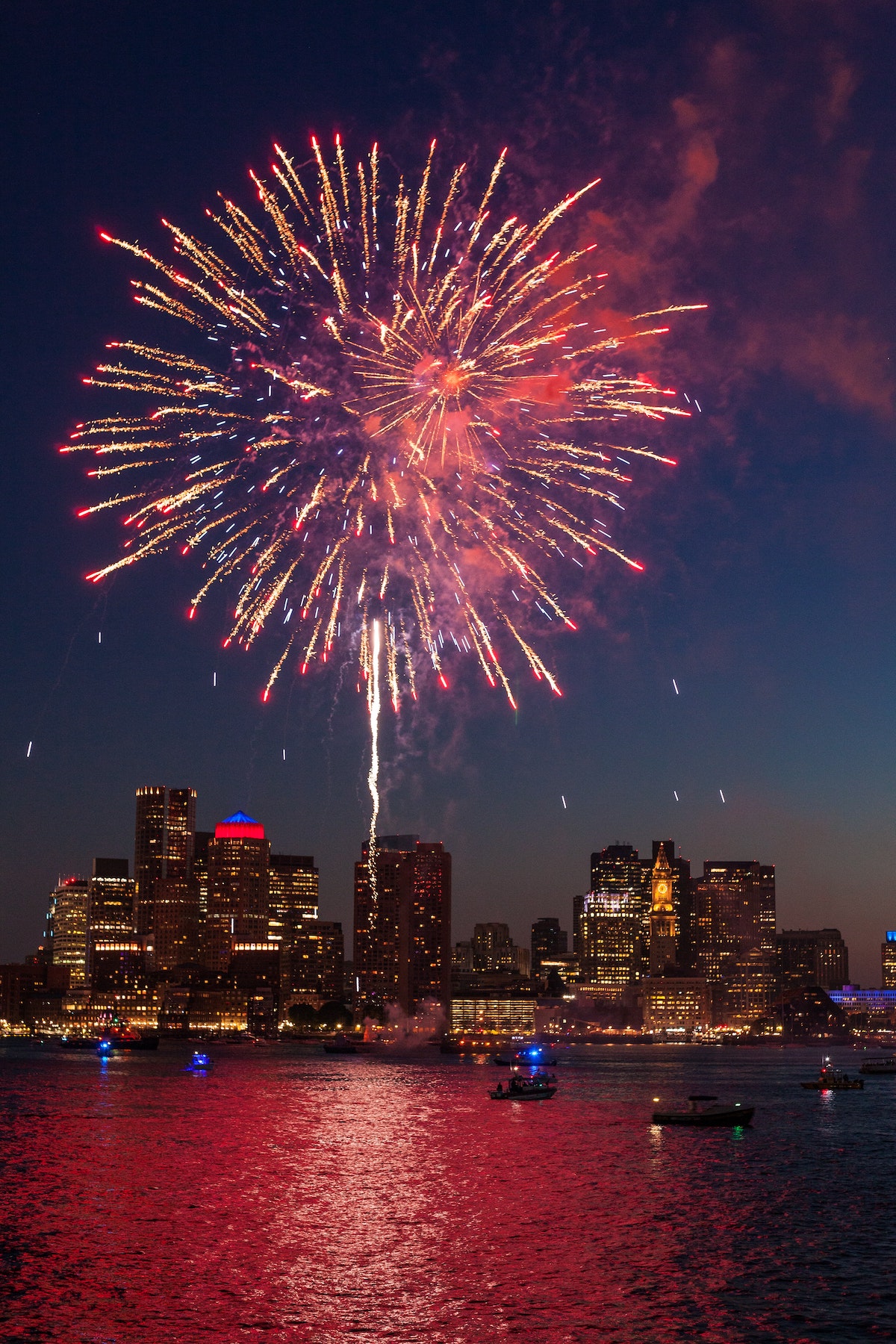 Un enorme fuego artificial rojo y blanco estalla sobre el horizonte de Boston el 4 de julio, uno de los festivales más divertidos de Boston.