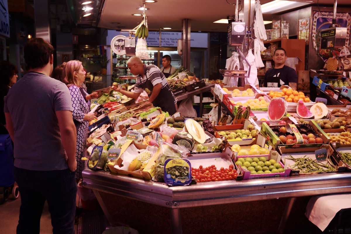 Gente comprando en un puesto de productos frescos dentro de un mercado