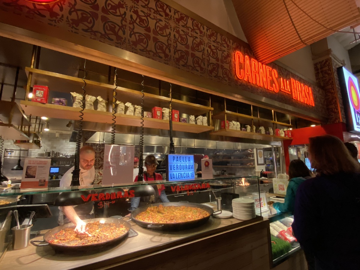 Un puesto en el mercado con dos grandes sartenes de paella en el mostrador