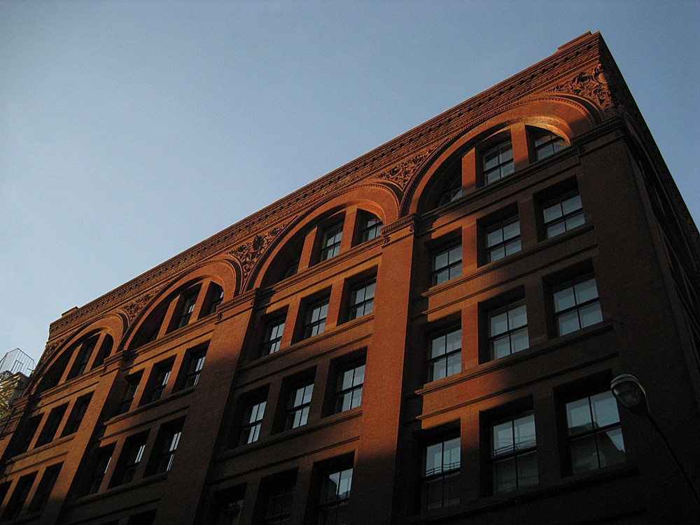 Puesta de sol en un edificio alto de ladrillos con muchas ventanas y columnas