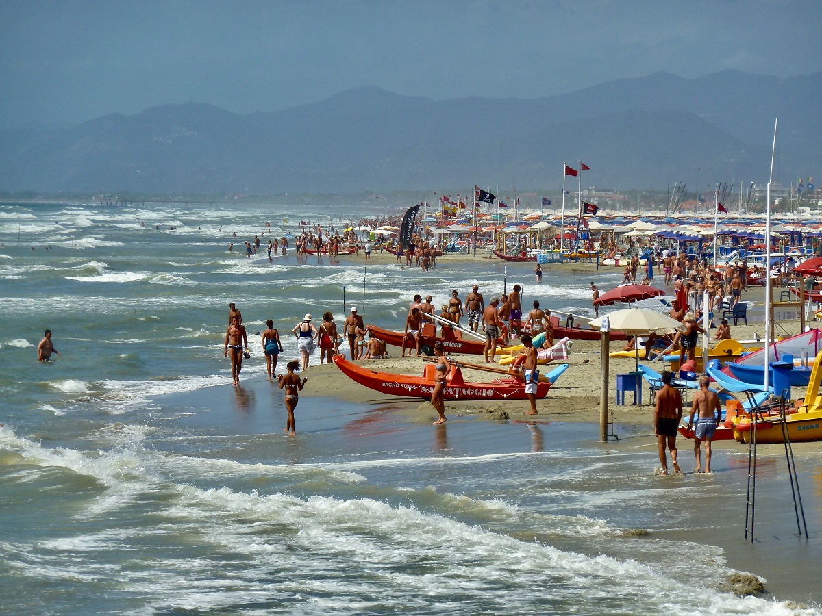 Personas y botes pequeños en una playa de arena en Italia