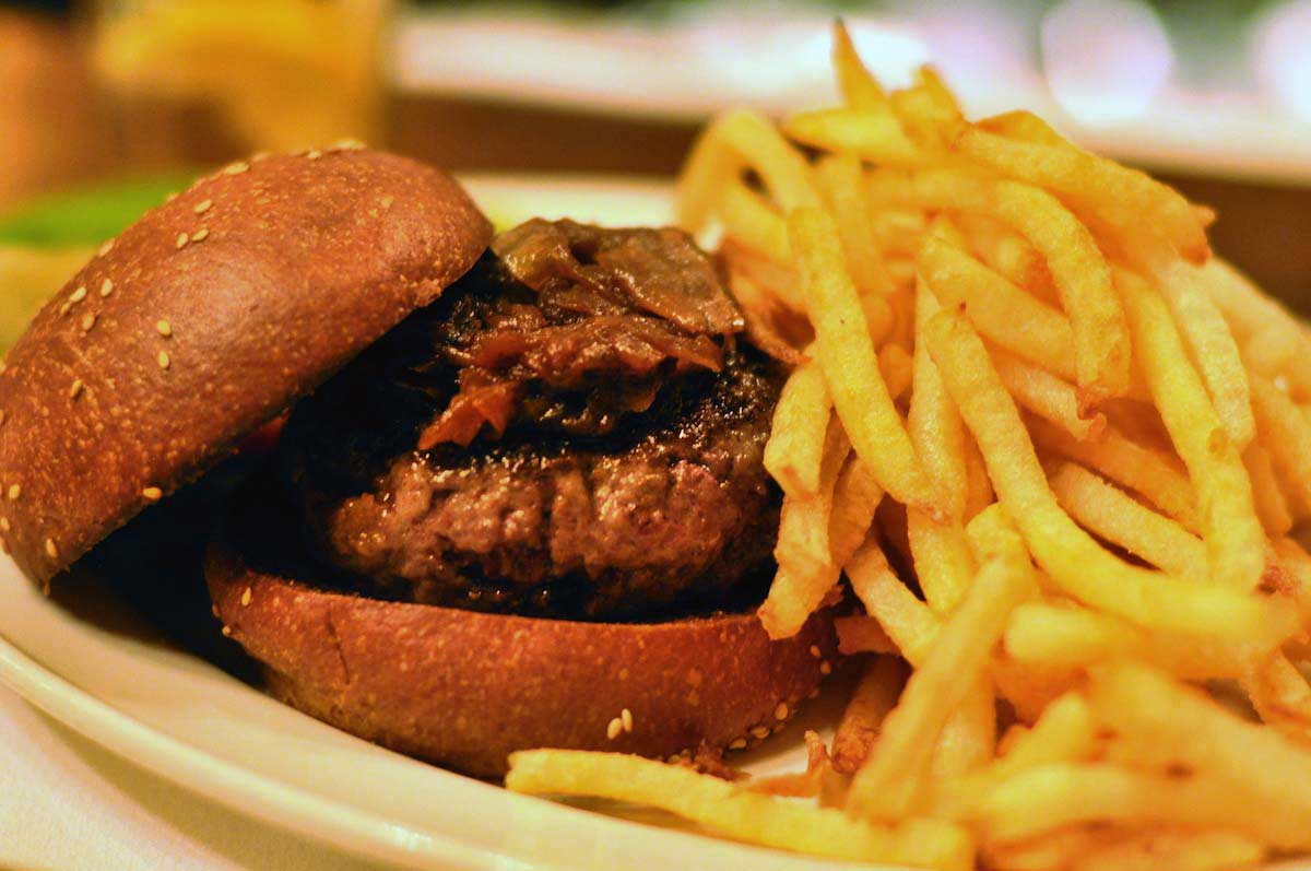 Una hamburguesa junto a una gran pila de papas fritas