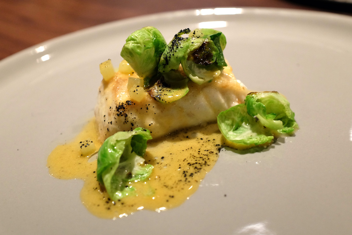 Halibut con coles de Bruselas servido sobre una cama de salsa amarilla