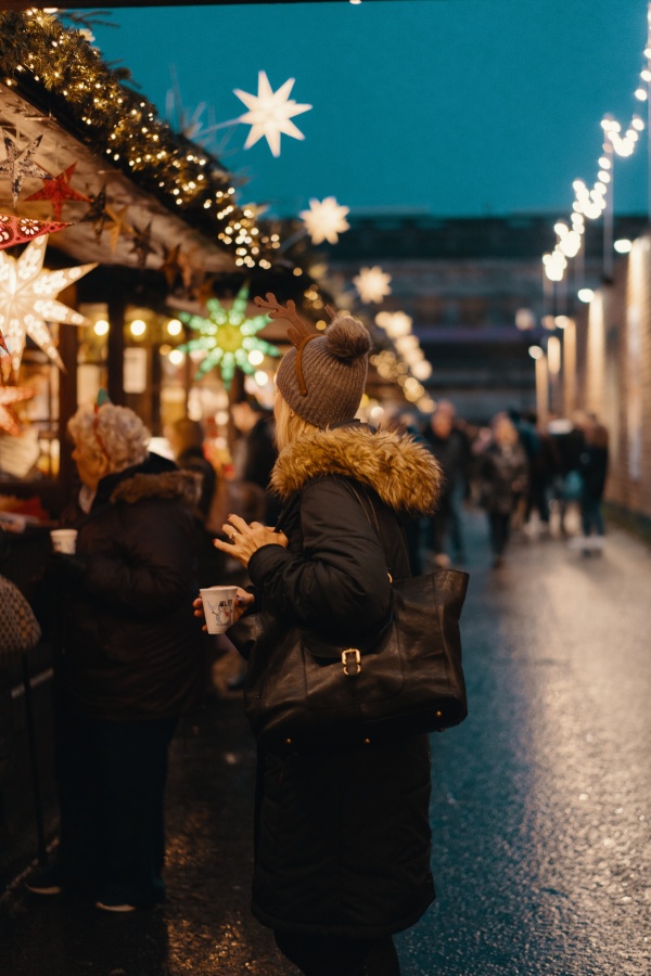 Una mujer sostiene una copa de vino caliente en un mercado navideño en París.
