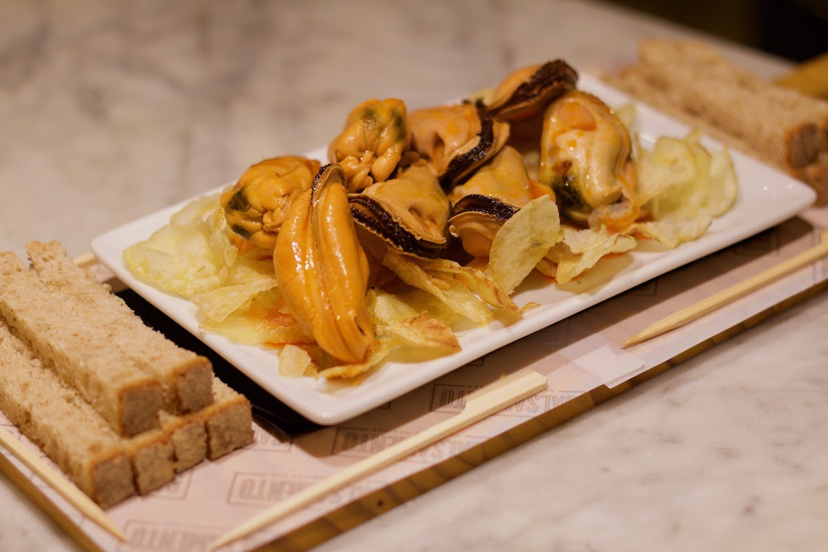 Mejillones enlatados servidos con papas fritas en una tabla de madera