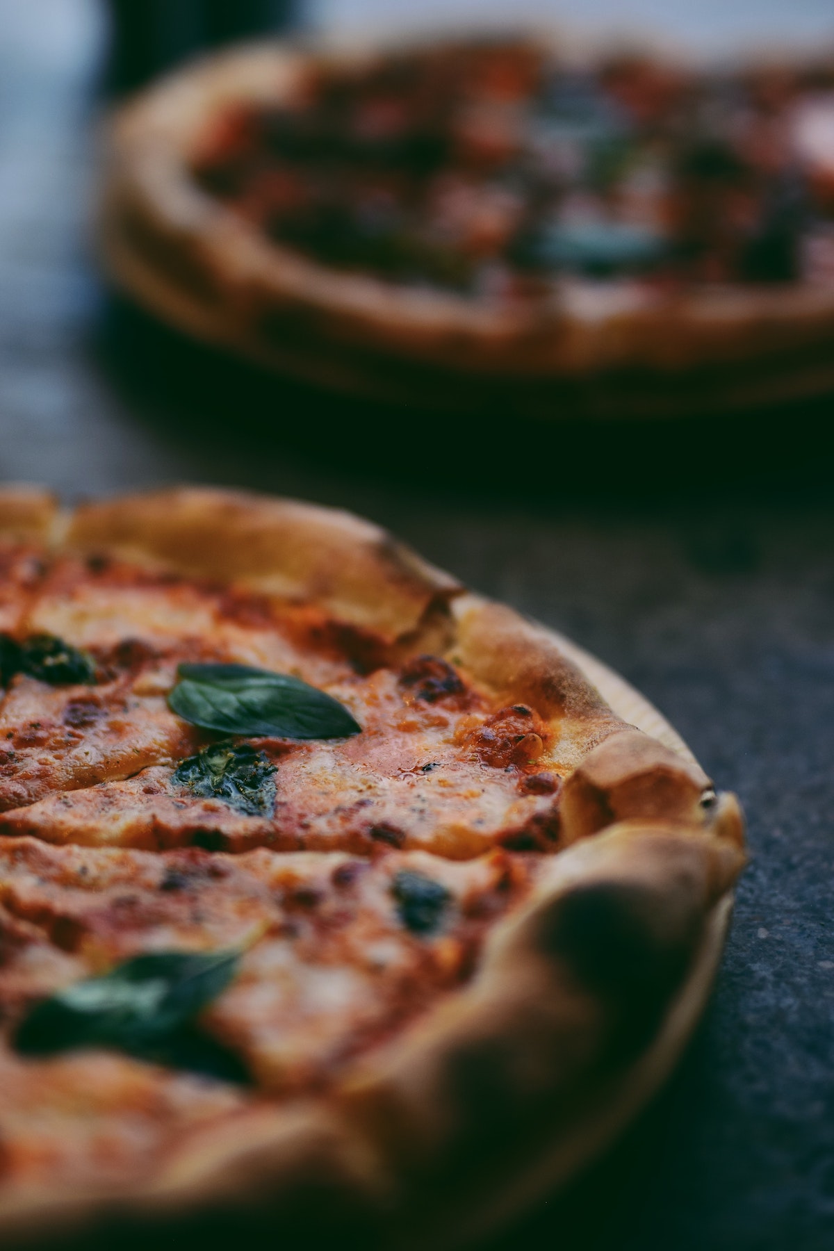 Cerca de la mitad de una pizza de masa gruesa adornada con albahaca