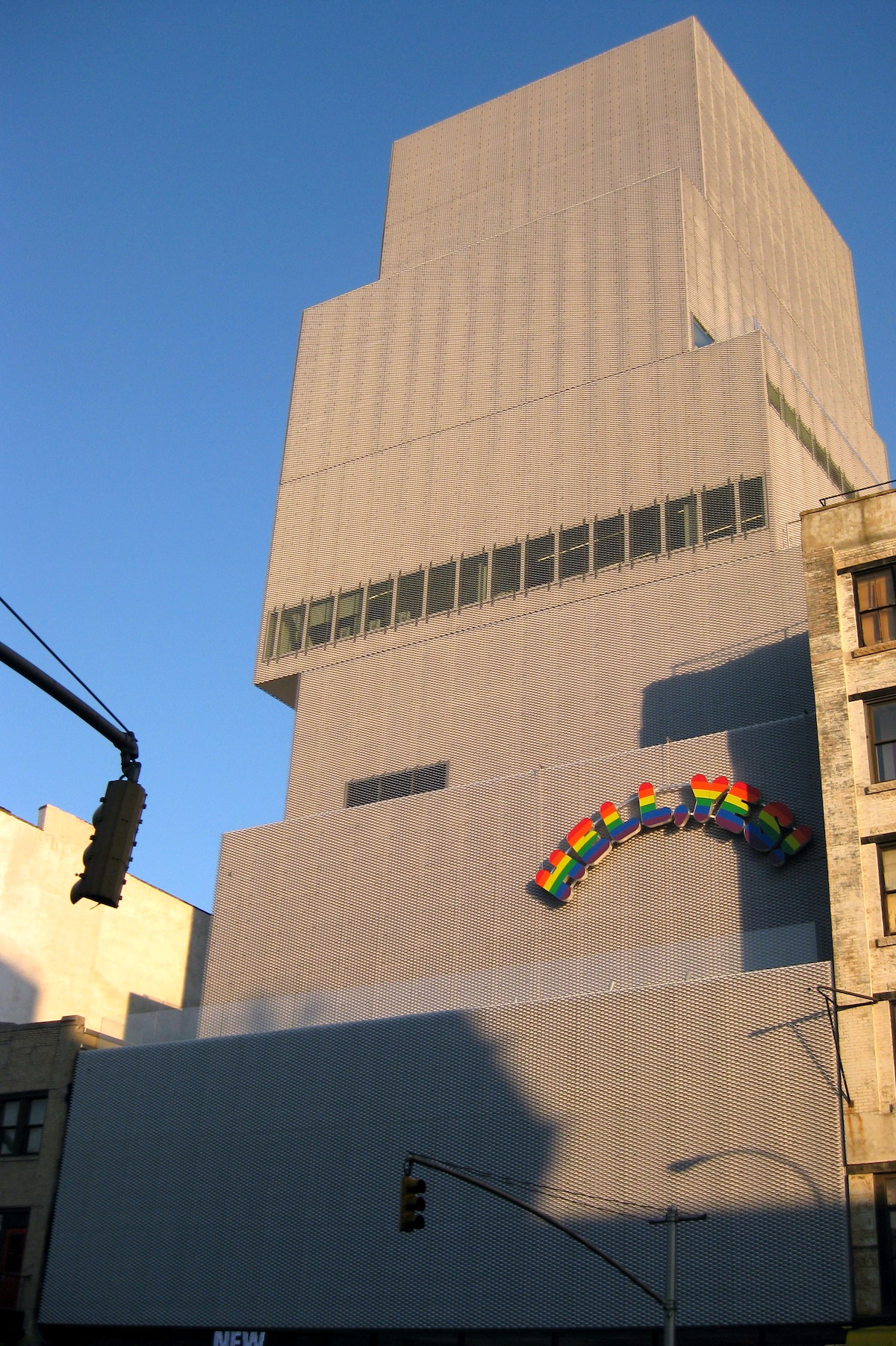 Un edificio gris contemporáneo con letras de arcoíris que dicen "Hell There Is" en el lado derecho