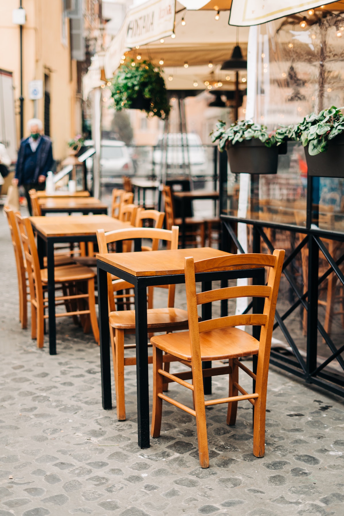Mesas y sillas de madera en un café en la acera en Italia