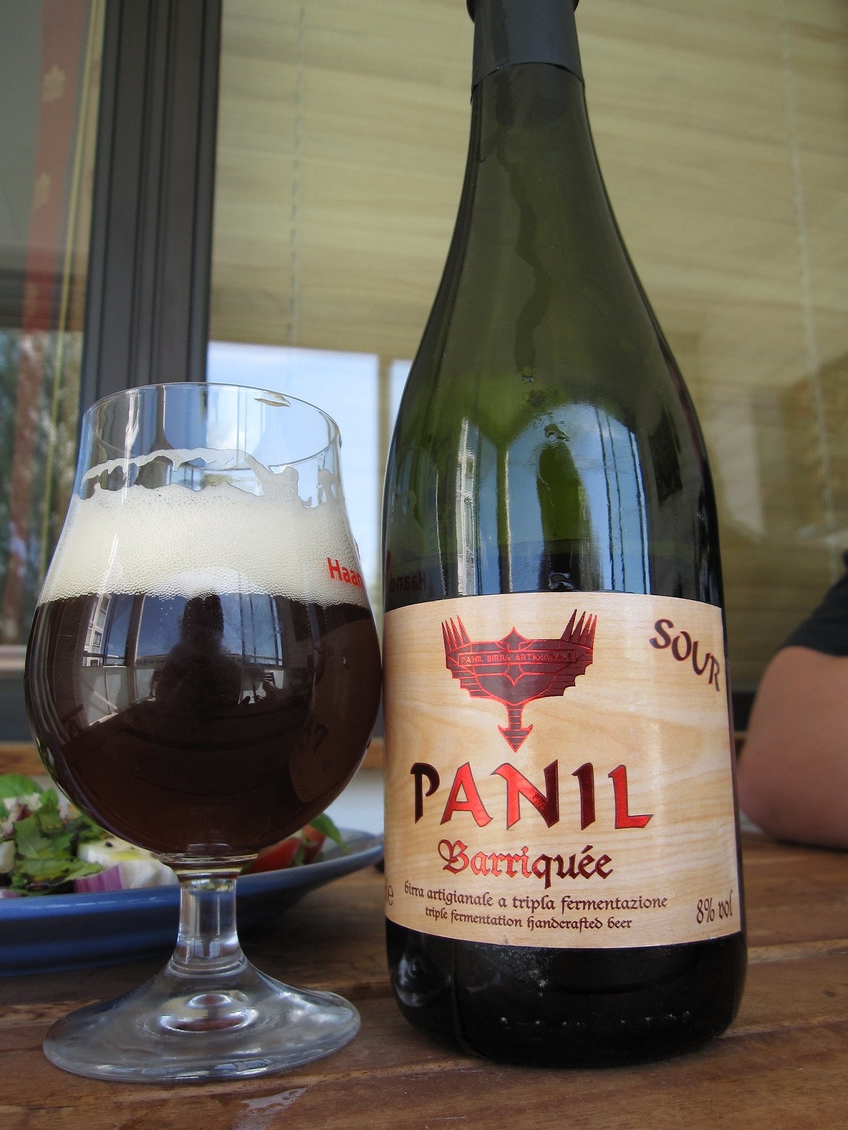 Una botella grande de vino Panil Barriquee de Italia junto con una jarra de cerveza negra