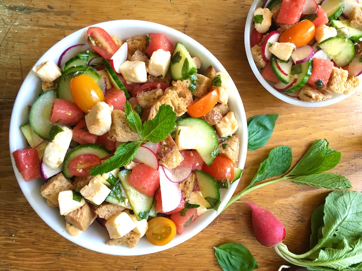 Fotografía cenital de un tazón grande y uno pequeño de ensalada de pan toscano con verduras