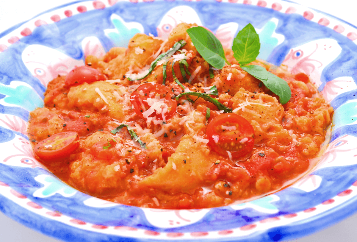 Un primer plano de una sopa de tomate típica toscana en un recipiente azul y blanco