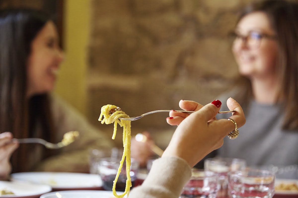 Cerca de espaguetis en un tenedor en la mano de alguien