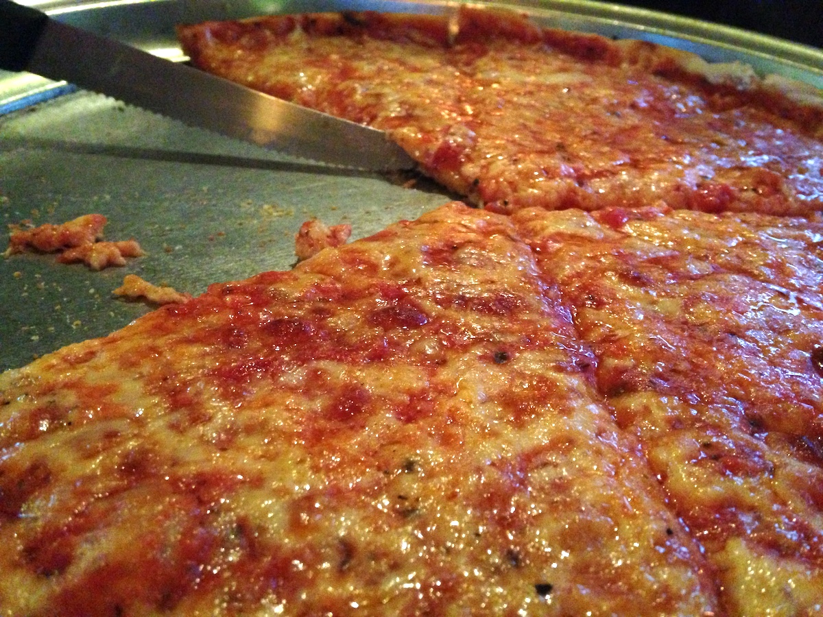 Cerca de pizza cortada en rebanadas individuales en una fuente de metal