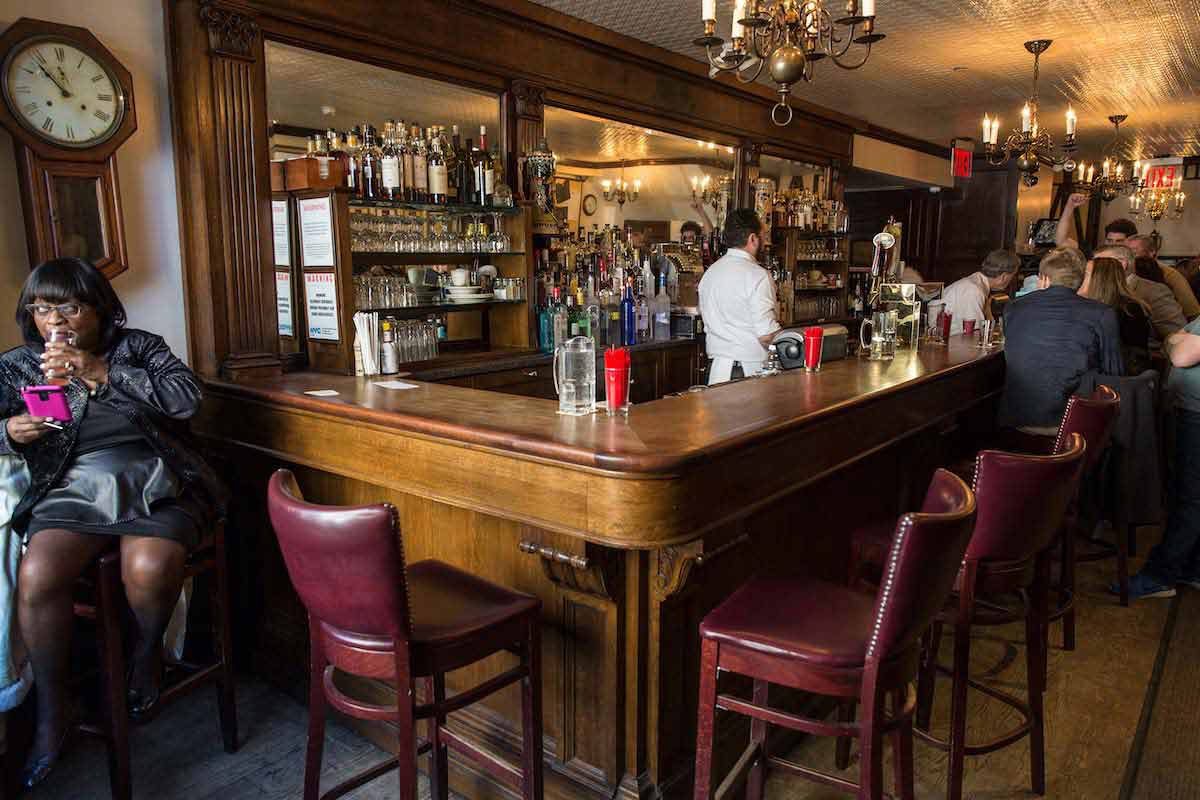 Bar con paneles de madera oscura y sillas de cuero rojo.