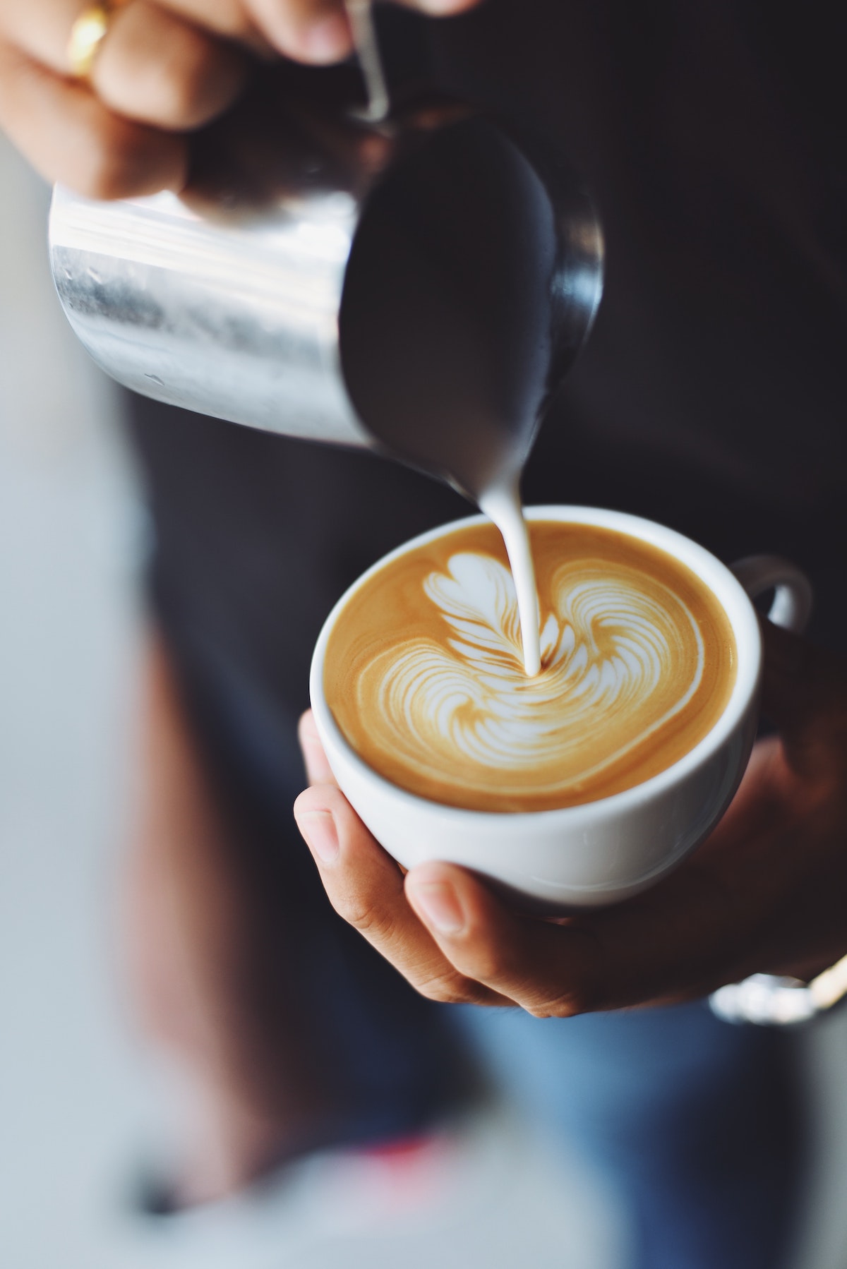 Una persona vierte espuma de leche sobre el café para hacer un arte de capuchino