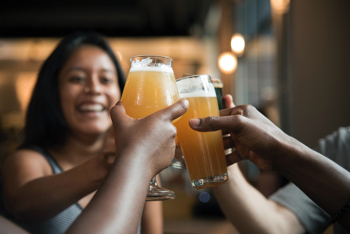 Mujeres sonrientes sosteniendo jarras de cerveza y vasos para animar