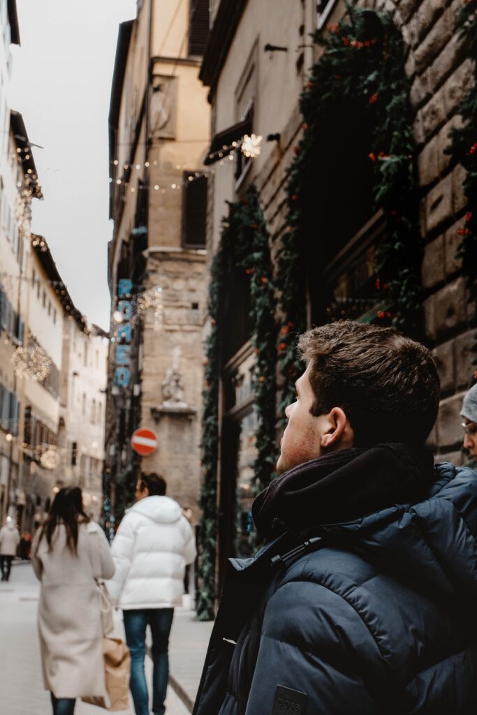 Un hombre camina por las calles de Florencia en invierno, con adornos navideños en las tiendas
