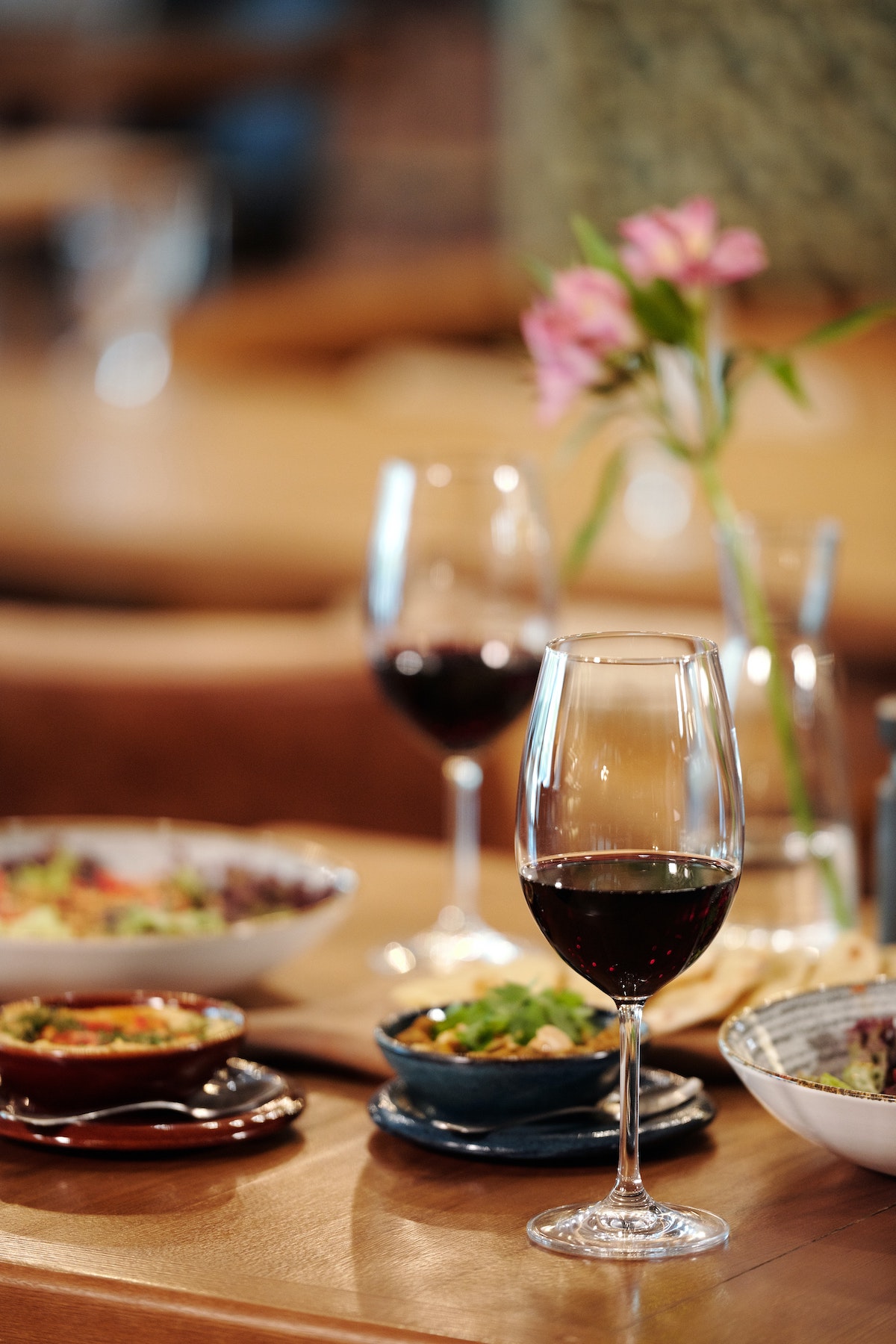dos copas de vino tinto y platos pequeños en una mesa de madera