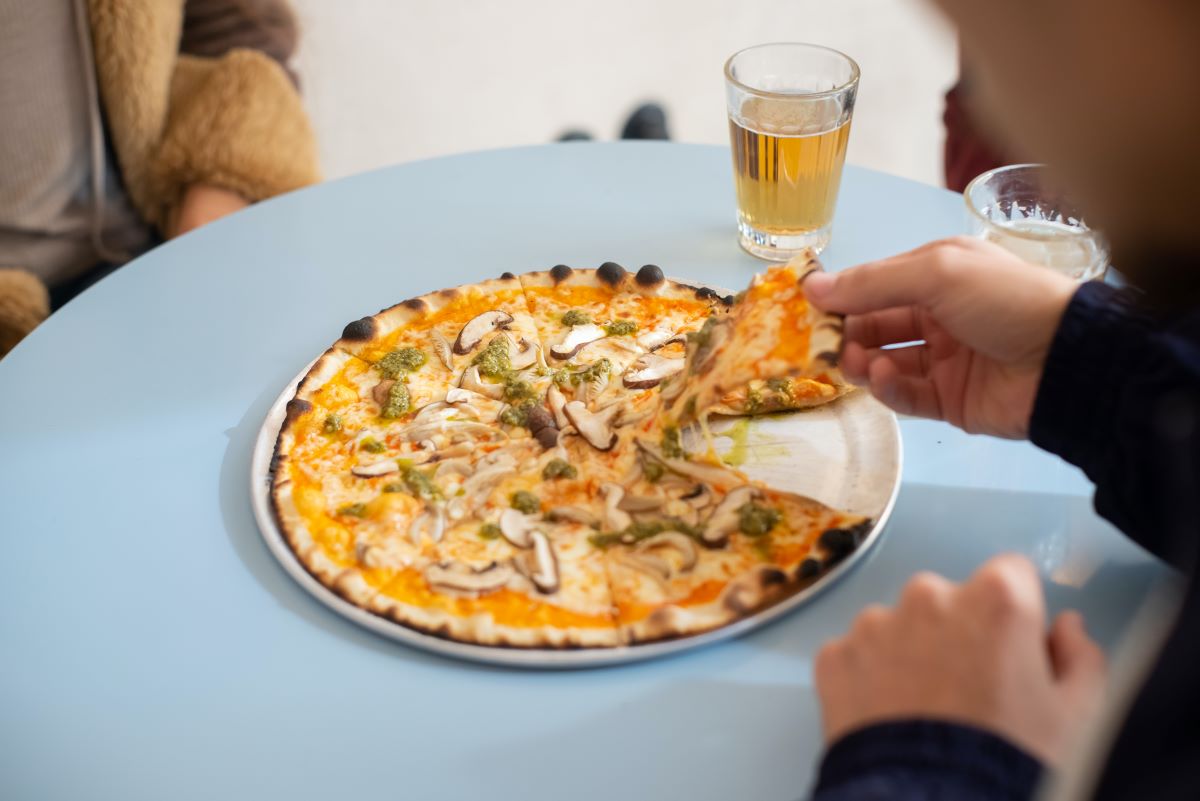 pizza con champiñones y un vaso de cerveza en la mesa azul