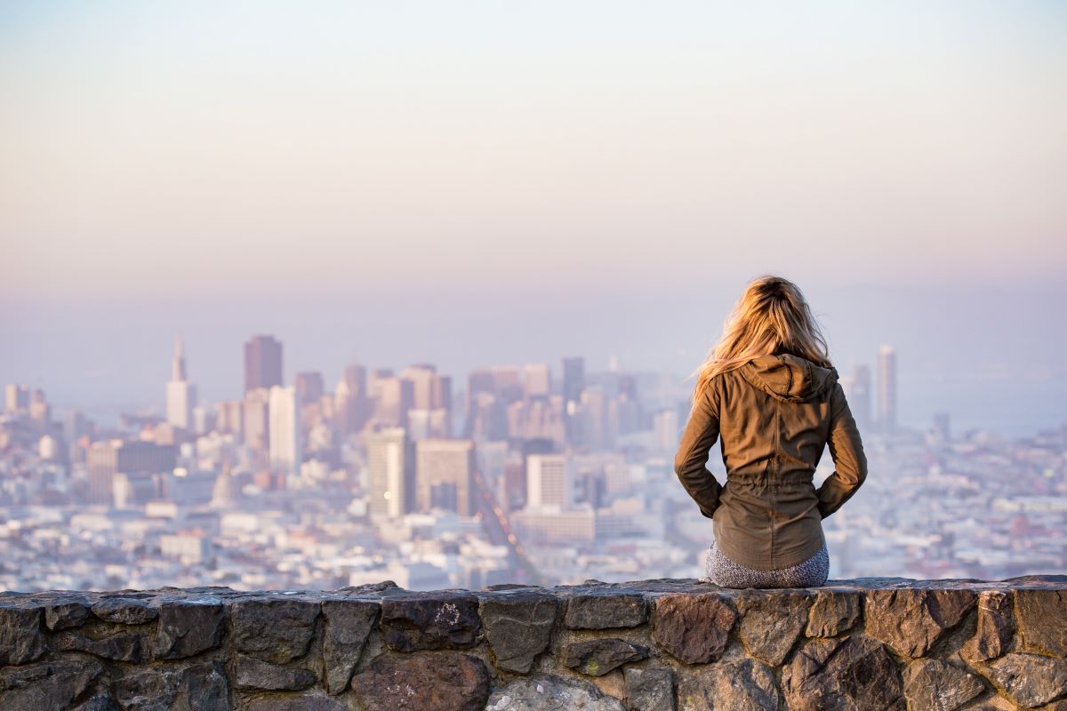 Una mujer soltera de Nueva York sentada en un muro de piedra con vistas al horizonte de Nueva York