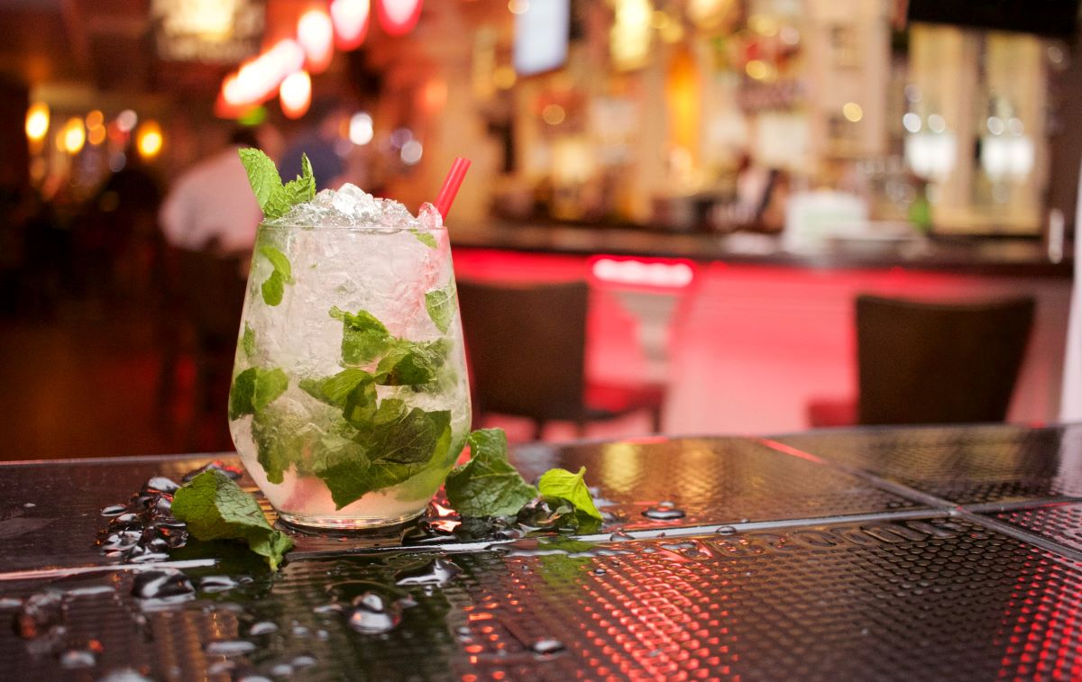 cóctel blanco con menta en un bar con luces de neón