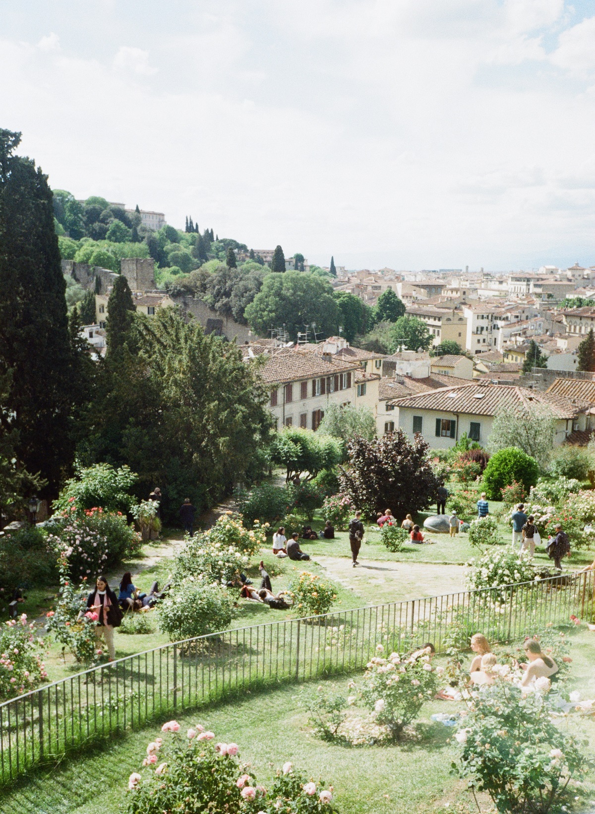 La rosaleda de Florencia con muchos visitantes relajándose en el césped