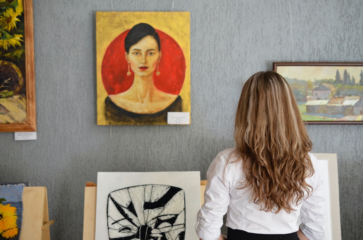 Una mujer con una camisa blanca mira un retrato de una mujer seria