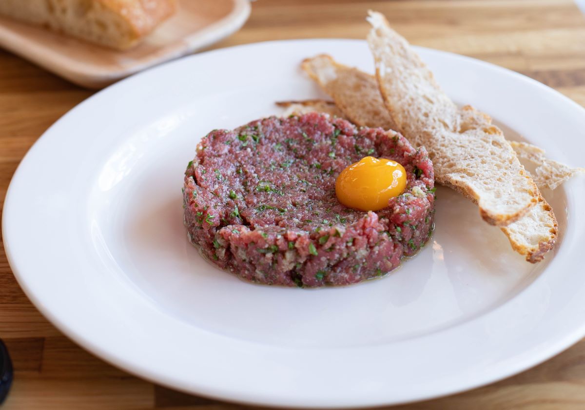 tartar de ternera en un plato blanco con yema de huevo y tostadas