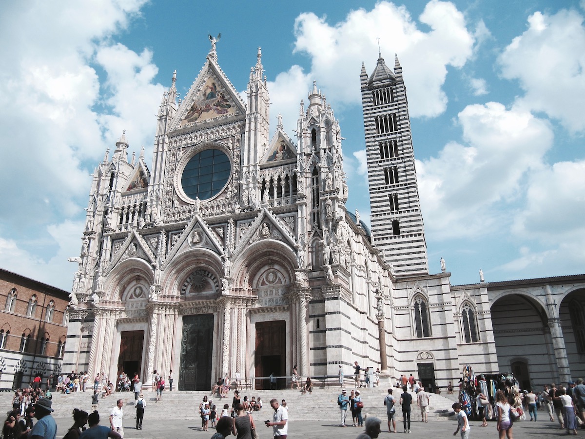 Catedral gótica blanca en una plaza italiana en un día mayormente soleado
