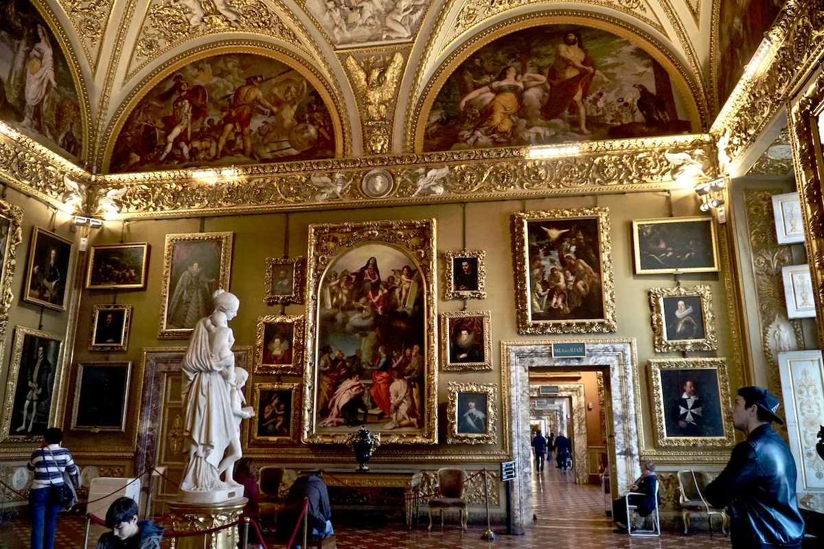 Una gran galería de arte con adornos dorados y una estatua de mármol de una mujer en primer plano