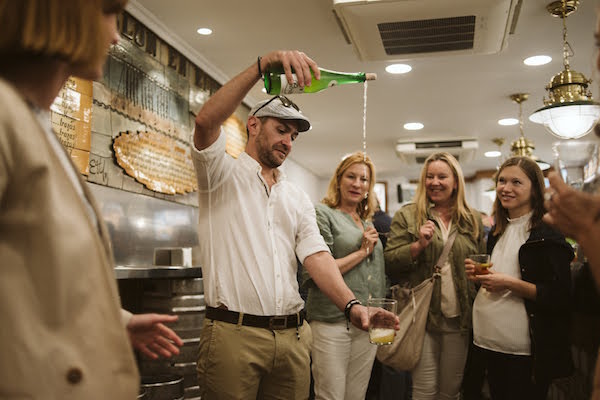 ¡Viajar responsablemente en San Sebastián puede ser divertido! Caso en cuestión: visite una sidrería tradicional y aprenda a verter la bebida refrescante y crujiente desde arriba.