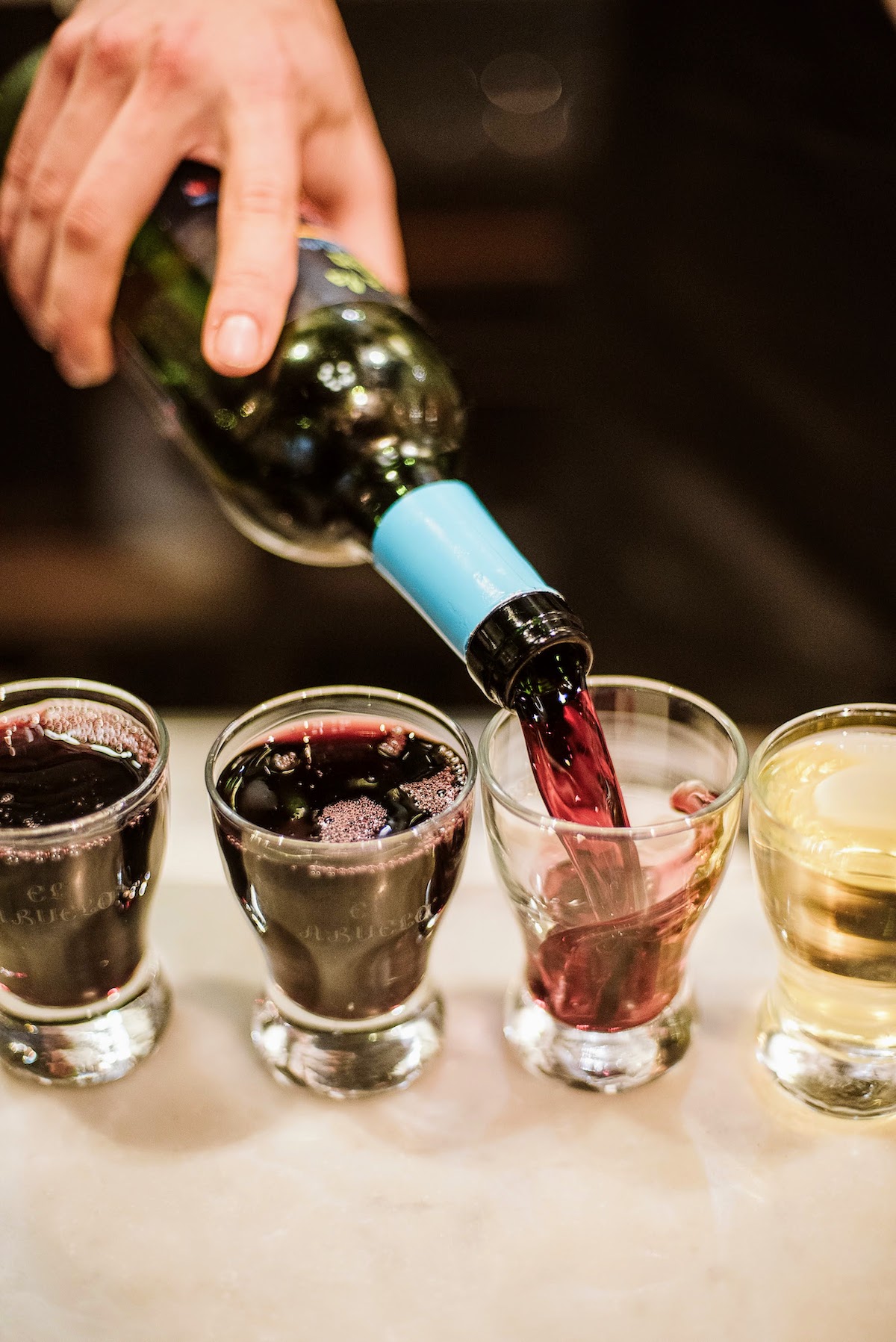 Se vierte vino tinto de una botella en pequeños vasos de conversación
