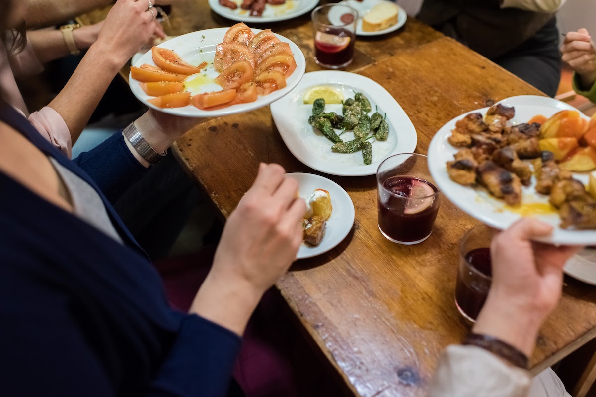 Gente pasando platos compartidos alrededor de una mesa