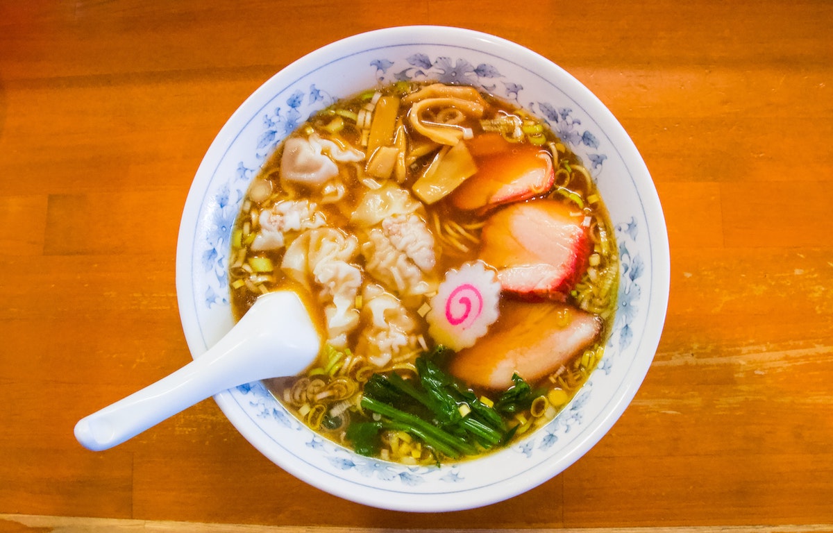 Coloque ramen encima con carne y verduras en un tazón blanco