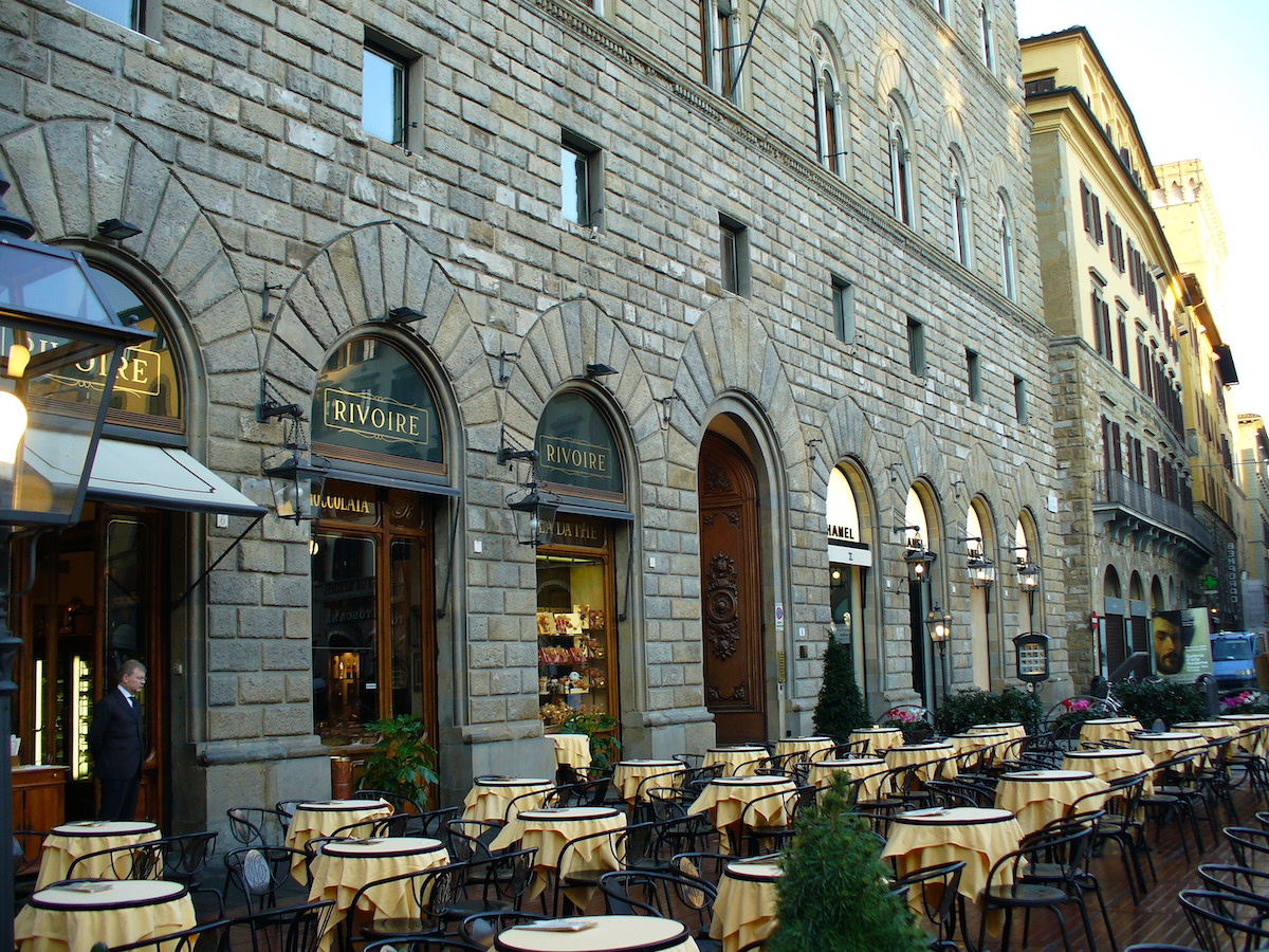 Una terraza de café al aire libre fuera de un gran edificio de piedra