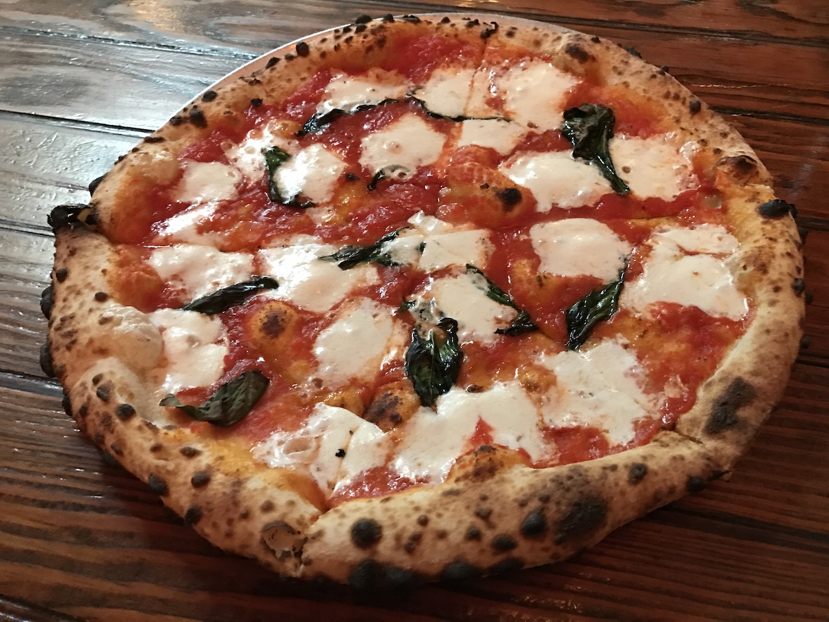 Pizza entera al estilo napolitano con queso mozzarella y albahaca