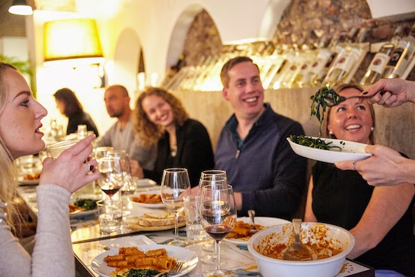 Un grupo de personas compartiendo una comida con pasta y vino en Roma