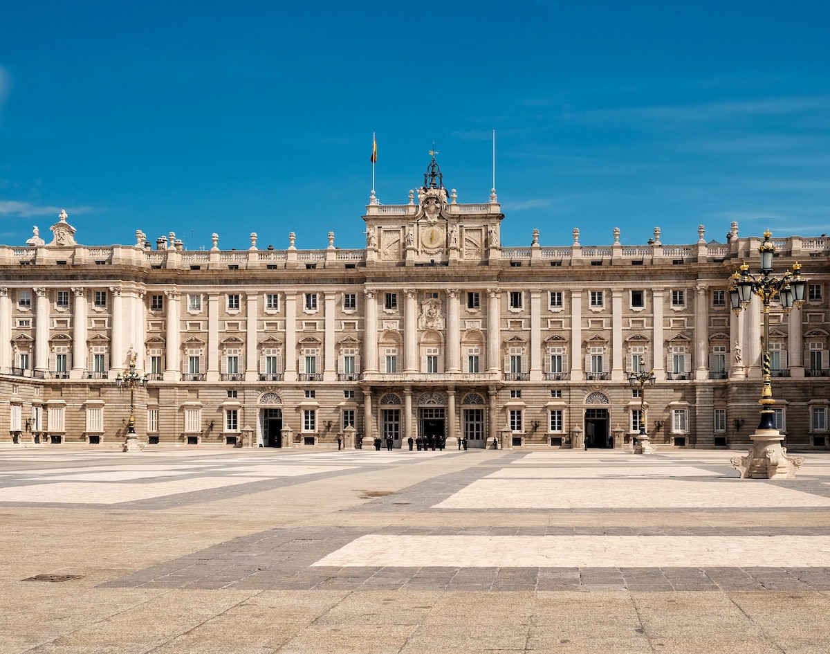 Afuera de un palacio real grande, grande, como se ve a través de una plaza espaciosa en un día despejado.