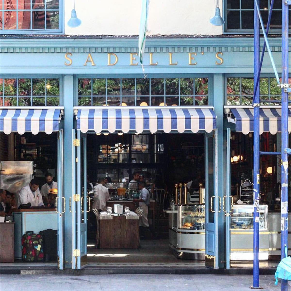 Exterior de Sadelle's en SoHo, Nueva York, con paneles azules y alas a rayas azules y blancas