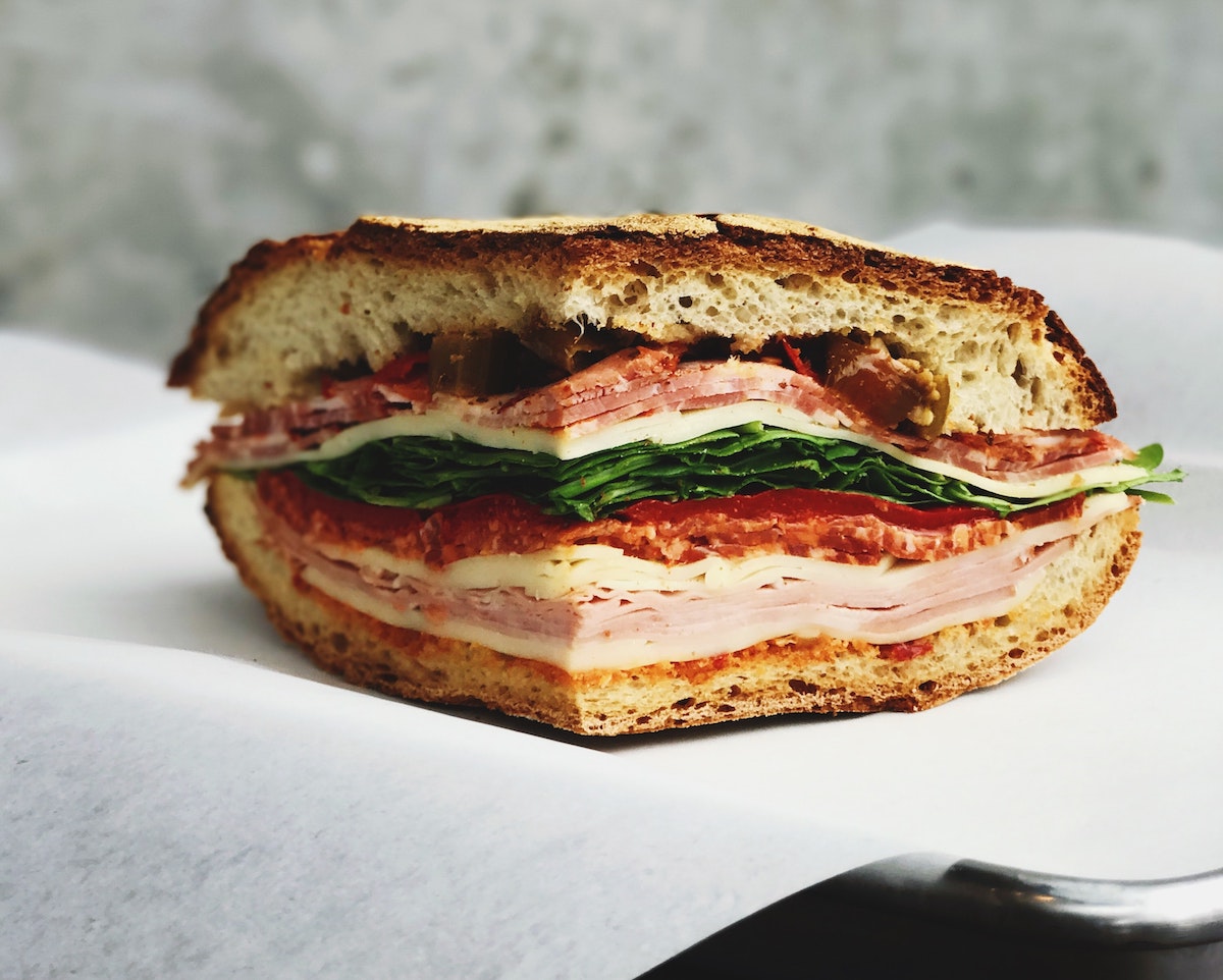 Primer plano de un sándwich lleno de fiambres y embutidos.