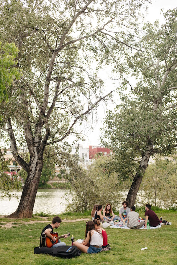Una de nuestras cosas favoritas para hacer en Sevilla en junio: relajarse en el parque junto al río antes de detenerse a tomar algo en el mercado gastronómico.