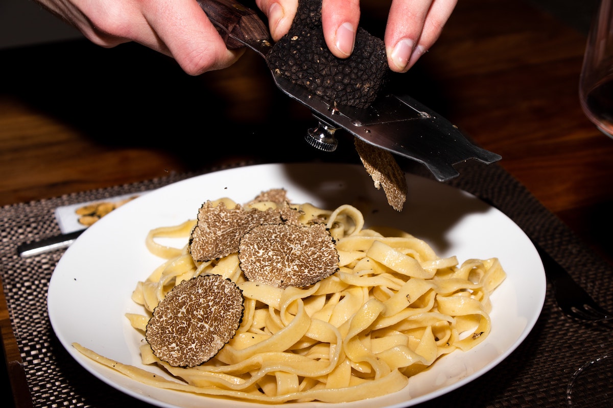 Las trufas se raspan suavemente sobre la parte superior de la pasta fettuccine.