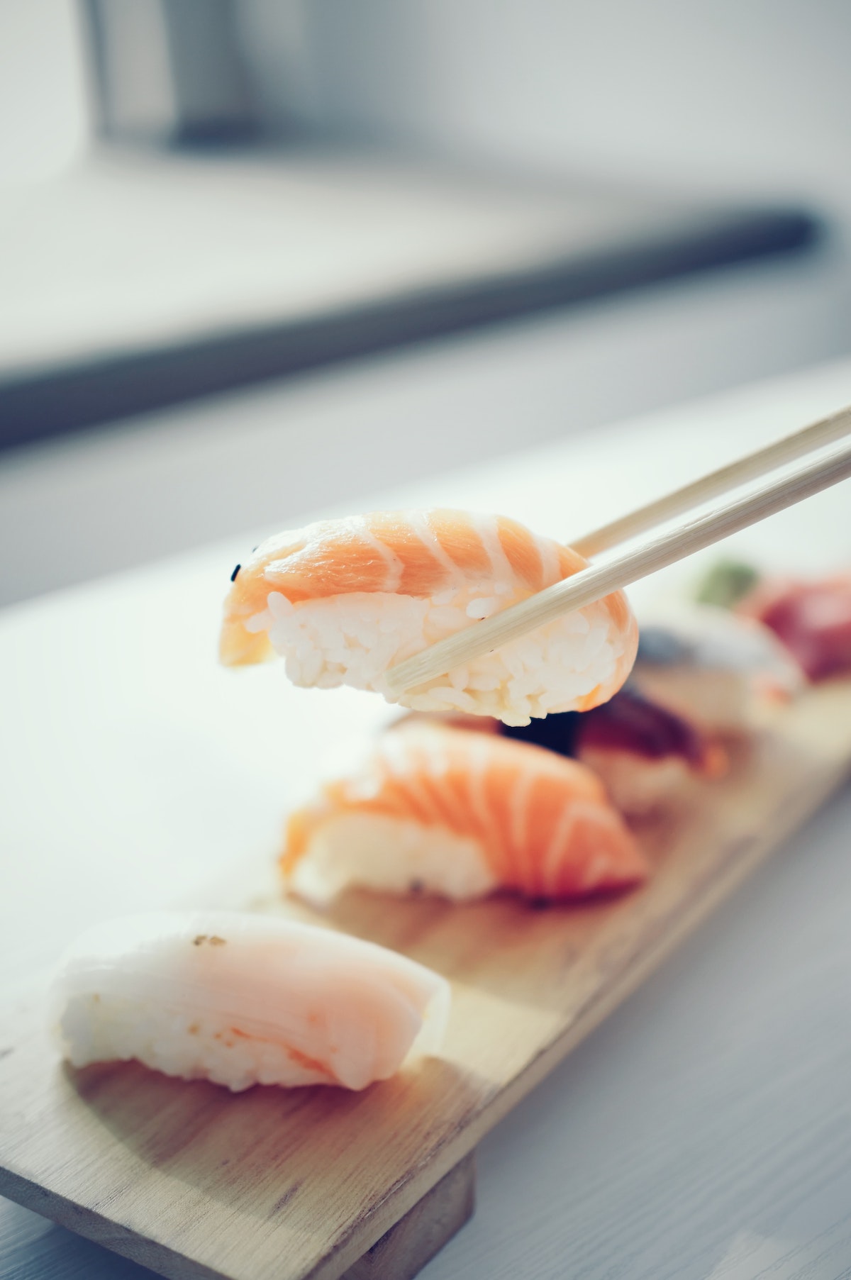 Sosteniendo un rollo de sushi de camarones sobre un plato pequeño de sushi con palillos